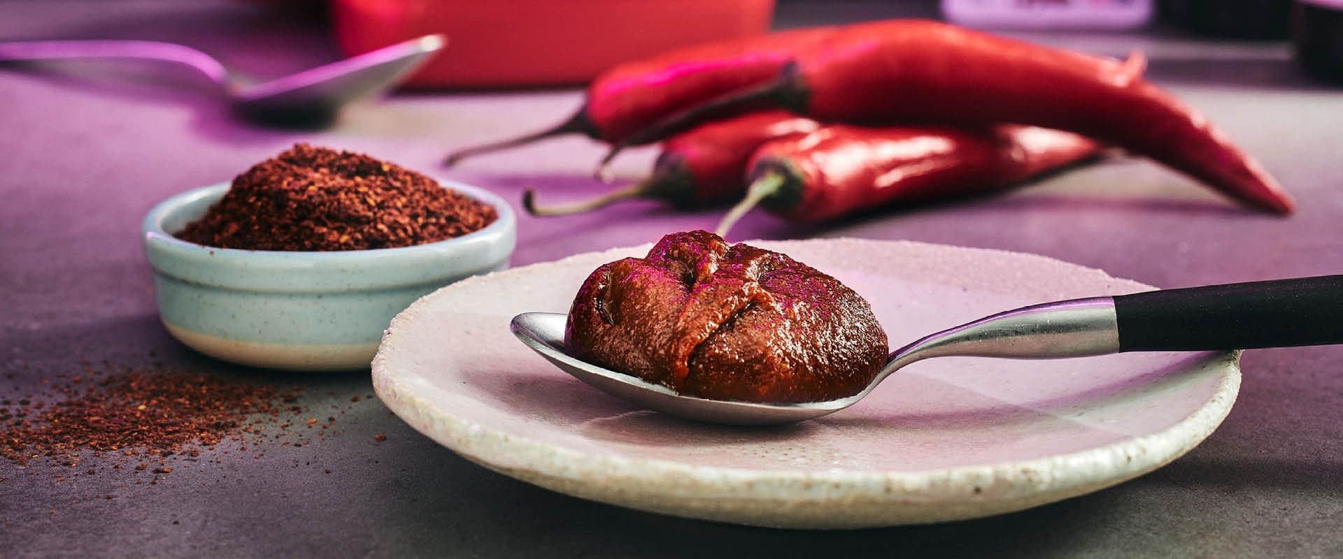 Skål med chilipulver och en sked med den koraenska chilipastan gochujang