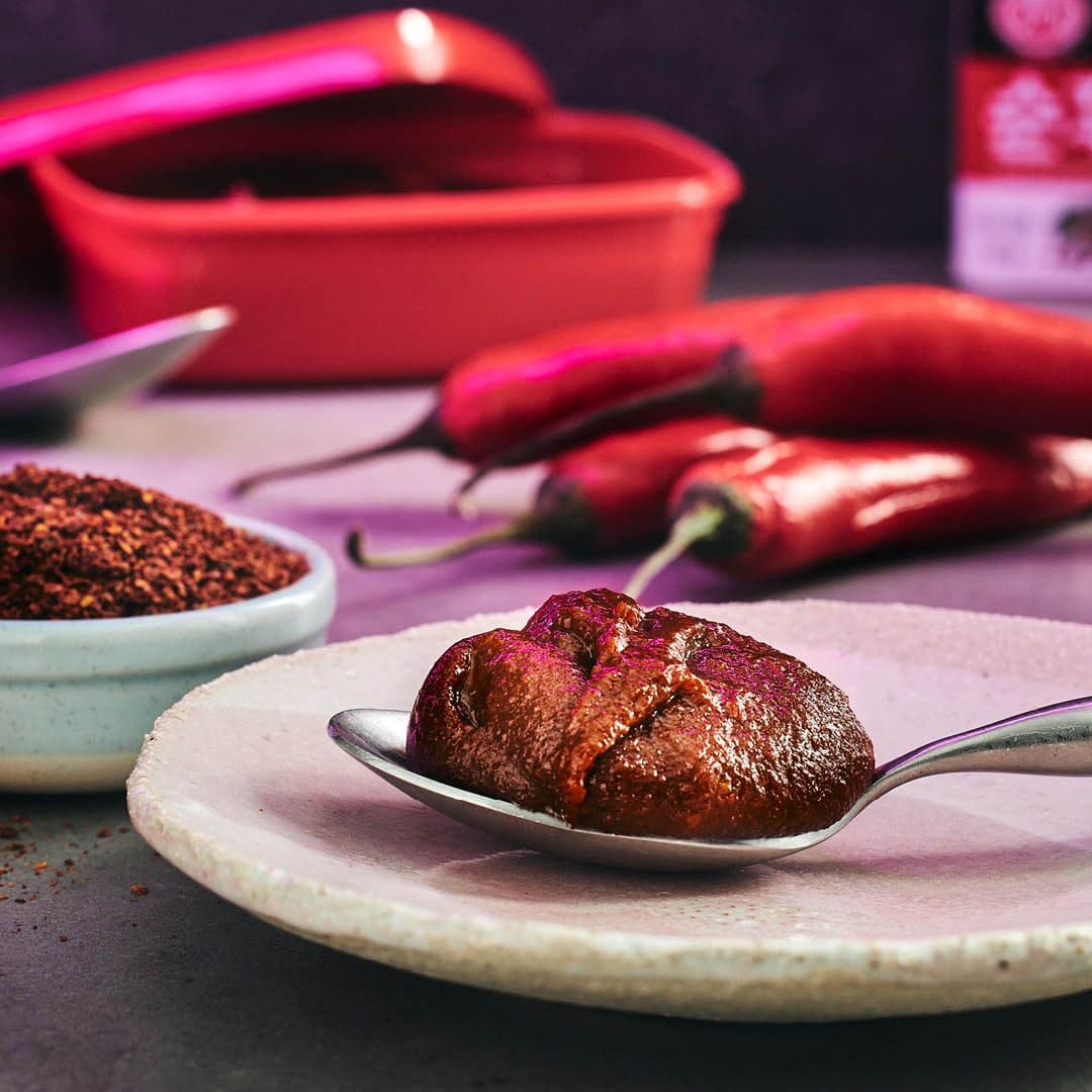 Skål med chilipulver och en sked med den koraenska chilipastan gochujang