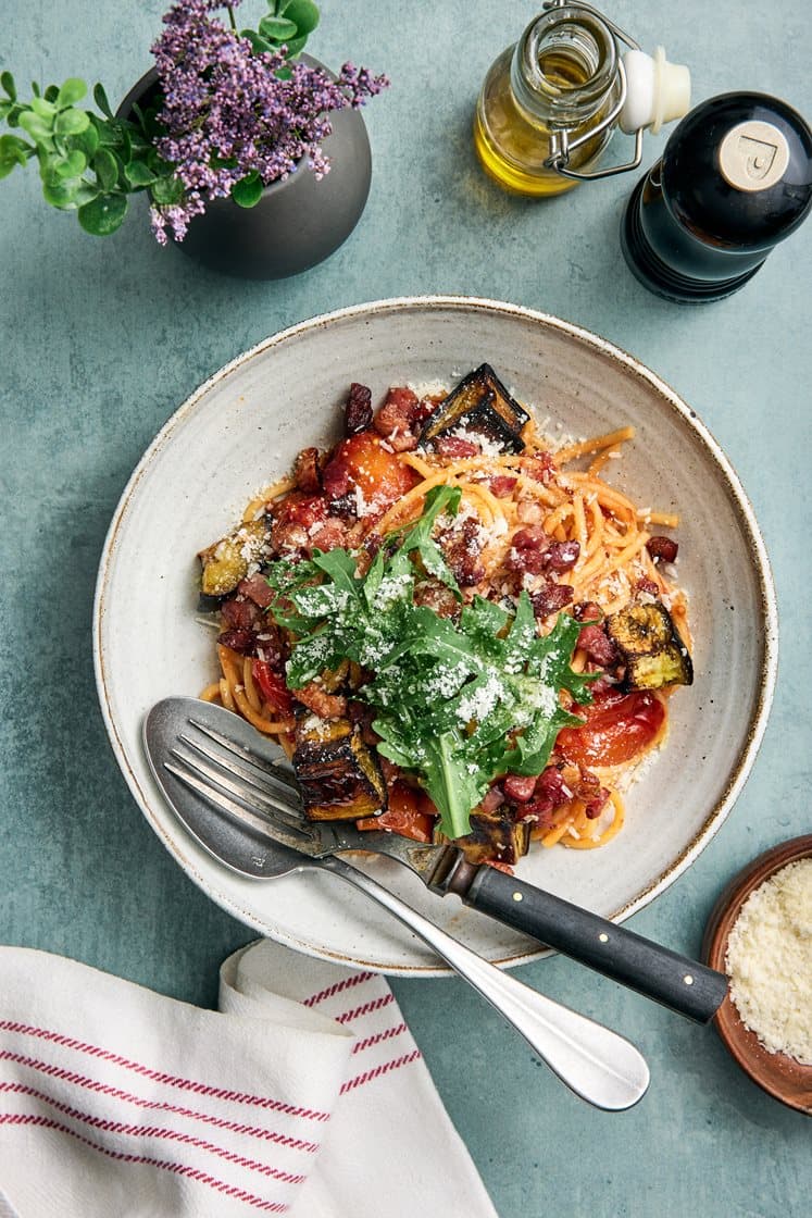 Spaghetti all arrabbiata toppad med knaprigt bacon, ruccola och parmesan