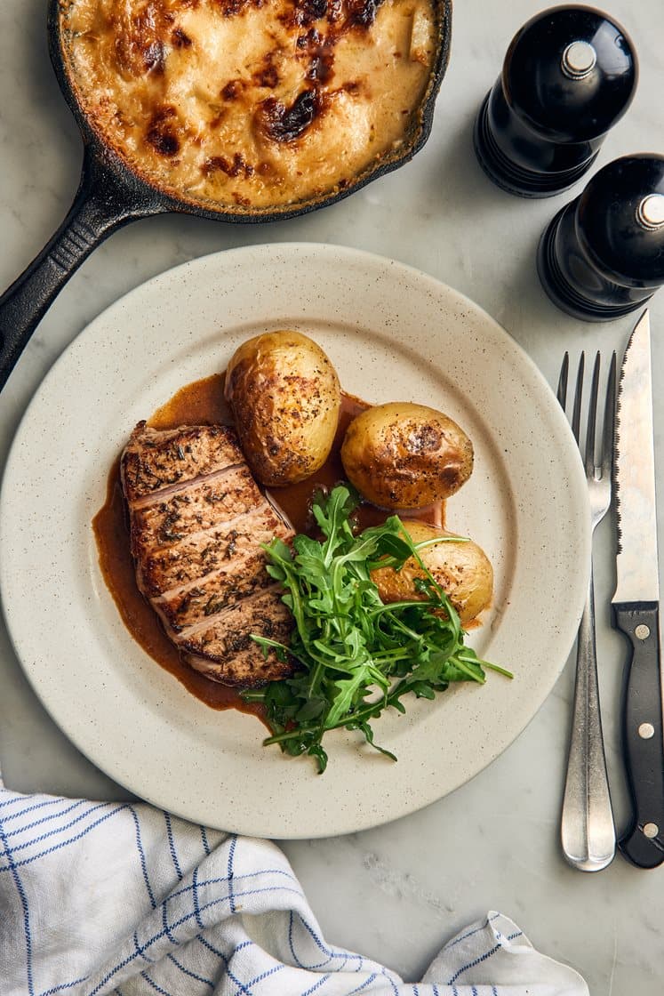 Timjanstekt fläskkotlett med jordärtskocksgratäng, parmesan och vitlökssky
