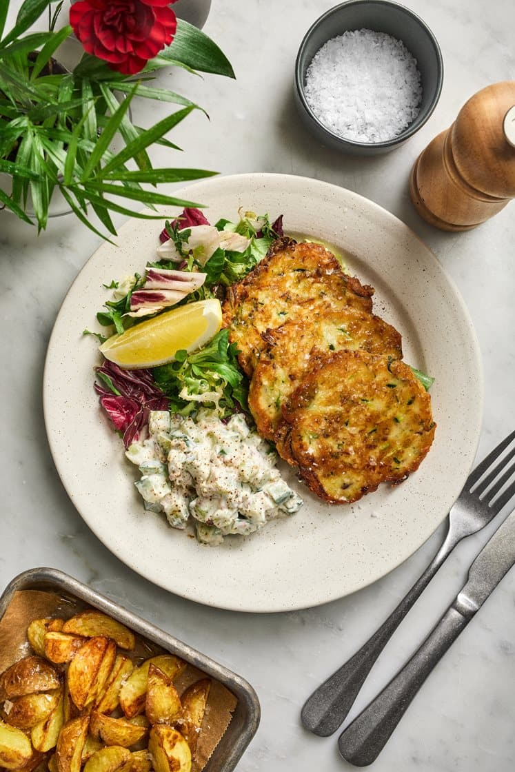 Zucchini- och cheddarplättar med klyftpotatis och krämig sallad